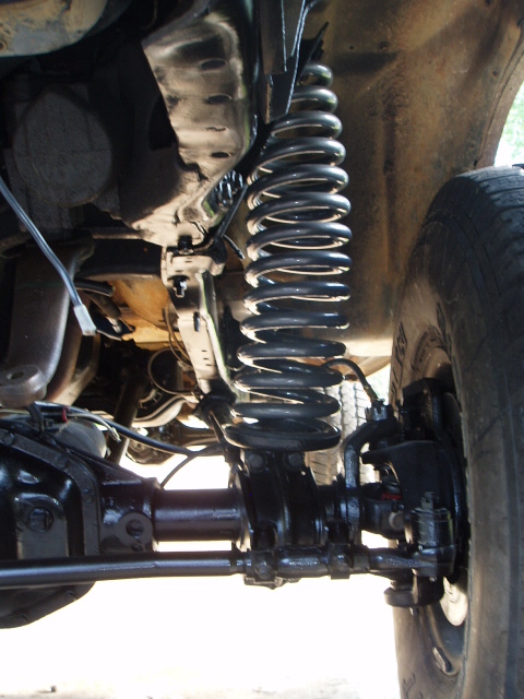 1980 Ford Bronco - Close-up of the undercarriage reveals the complex suspension and drivetrain of a vehicle.