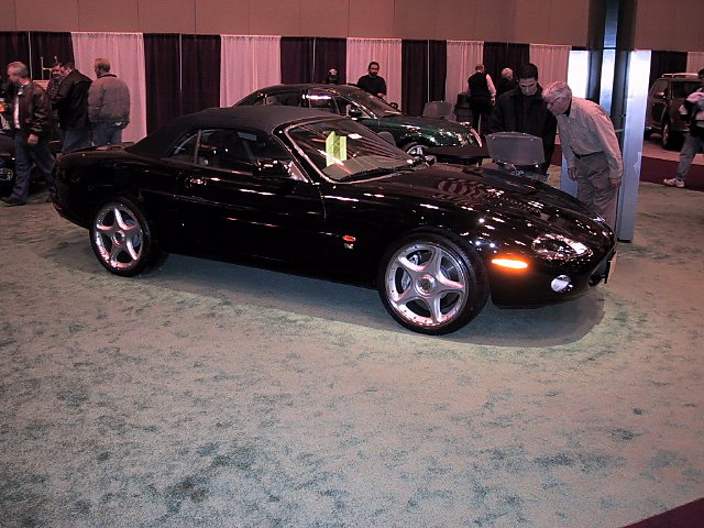 Black convertible sports car with five-spoke wheels at an auto show