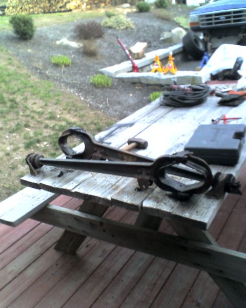 1996 Ford F-150 - Vehicle suspension parts are on a picnic table with tools and a blue truck in the background.