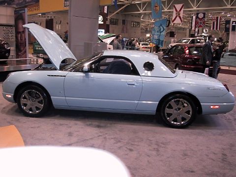 1996 Ford Taurus - A light blue Ford Thunderbird is displayed with its hood open at an auto show.