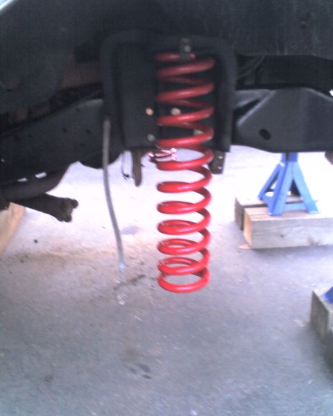 1996 Ford F-150 - Close-up of a red suspension spring on a vehicle undergoing maintenance.