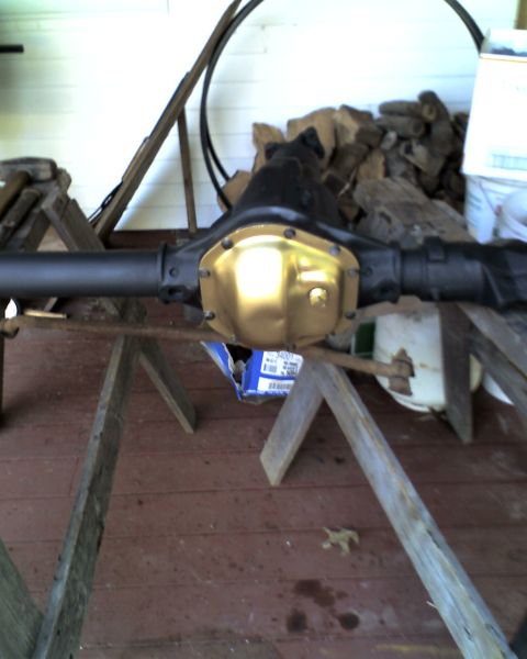 1996 Ford F-150 - A rear axle differential, likely from a truck, is shown with a gold-colored cover. The part is resting on wooden sawhorses outdoors.