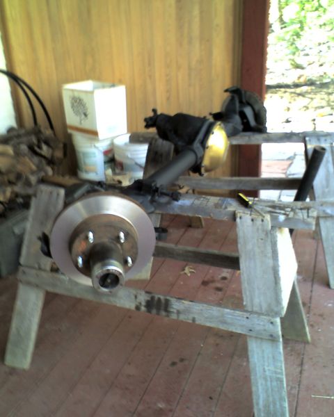 1996 Ford F-150 - Front axle assembly with brake rotor and caliper bracket, resting on wooden sawhorses.