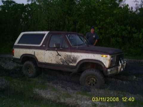 1982 Ford Bronco - This muddy 1982 Ford Bronco appears to be stuck in a muddy off-road area.