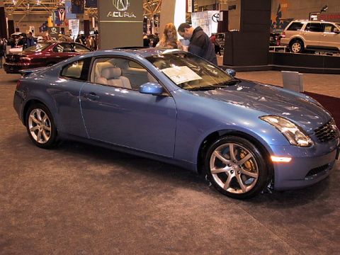 1996 Ford Taurus - A blue coupe is displayed at an auto show, with a red car and a white SUV visible in the background.