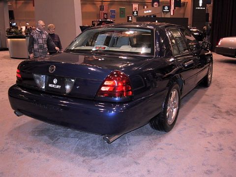 1996 Ford Taurus - A blue sedan is displayed indoors, possibly at an auto show, with people in the background.