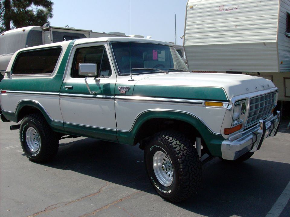 White and green Ford Bronco parked next to a trailer