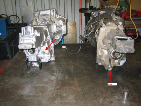1987 Suzuki Samurai - Two transmissions are shown on a workbench, one clean and one dirty, with arrows indicating fill and drain points.