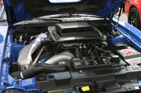 1992 Ford Crown Victoria - The engine bay of a blue vehicle is open, revealing a complex setup with a prominent air intake system.