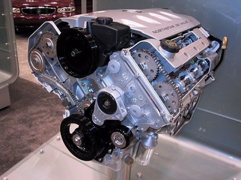 1996 Ford Taurus - A Northstar 32 Valve engine is displayed, with a red car partially visible behind it.