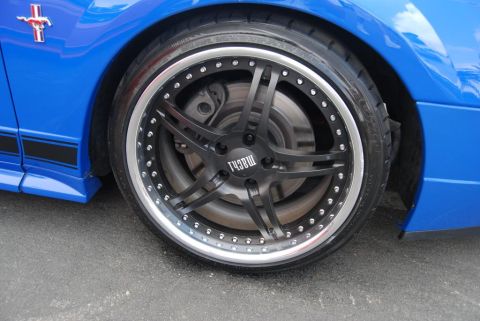 1992 Ford Crown Victoria - Close-up of a blue car's wheel and fender, showing custom rims and racing stripes.