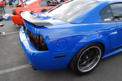 1992 Ford Crown Victoria - A blue Ford Mustang is parked at a car show, with an orange car visible behind it.