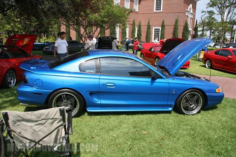1992 Ford Crown Victoria - Blue Ford Mustang coupe with hood open at a car show, other cars visible in background.