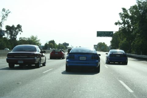 1992 Ford Crown Victoria - A blue Ford Mustang drives on the highway, with other vehicles around it.