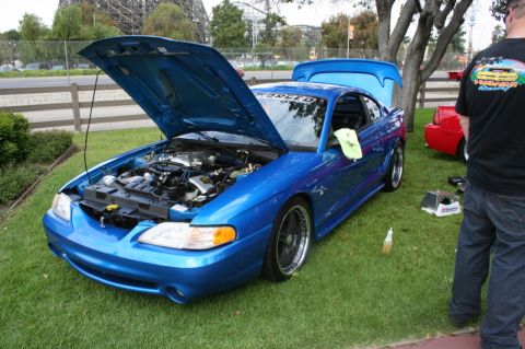 1992 Ford Crown Victoria - Blue Ford Mustang with hood and trunk open at an outdoor car show.