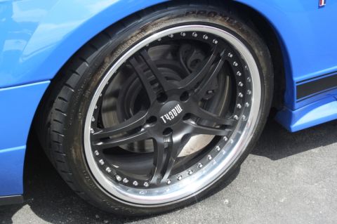 1992 Ford Crown Victoria - Close-up of a blue car's wheel and fender, with "MACH1" visible on the wheel's center cap.