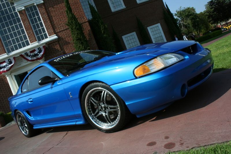 Blue 1996 Ford Mustang Cobra parked in front of a brick building