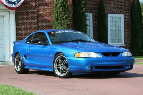 1992 Ford Crown Victoria - A blue coupe with a cobra emblem and a banner on the windshield sits in front of a brick house.