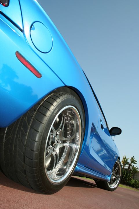 1992 Ford Crown Victoria - Low angle view of a blue car's rear quarter panel, custom chrome wheels and a clear sky.