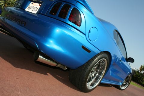 1992 Ford Crown Victoria - Rear view of a blue Ford Mustang Cobra, showing "COBRA" badging and a California plate.