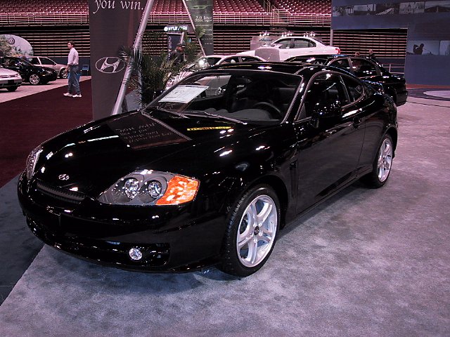 Black coupe with chrome wheels on display at an auto show