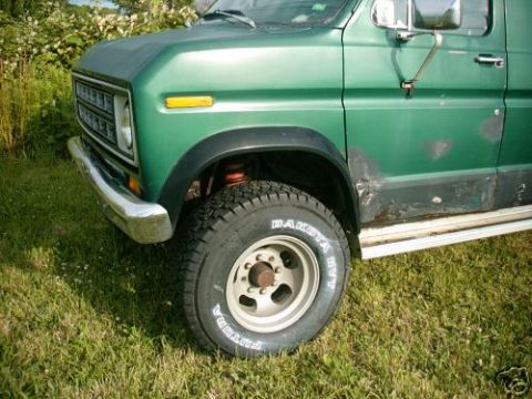 1978 Ford E250 - A green van with visible body damage and a chrome bumper is parked on grass.