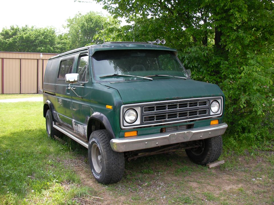 Green van with off-road tires and chrome bumper, parked on grass
