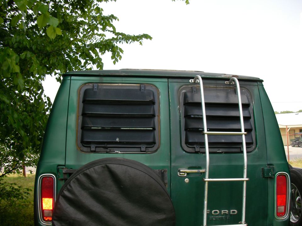 Green 1978 Ford E250 van rear view with louvred windows and a ladder