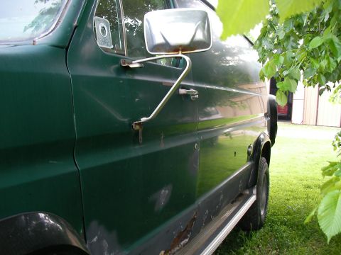 1978 Ford E250 - The side of a green van is shown, with visible rust on the lower body panels and a chrome trim piece.