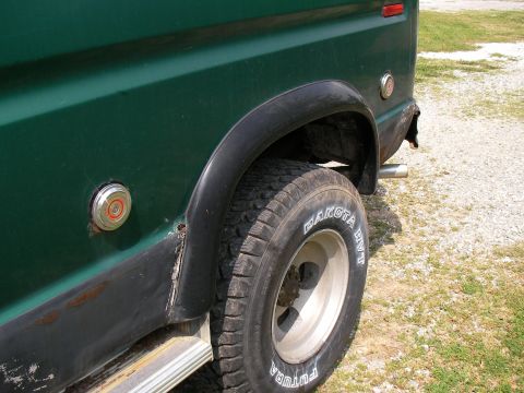 1978 Ford E250 - Close-up of the rear wheel well of a green van, showing the tire and side panel details.