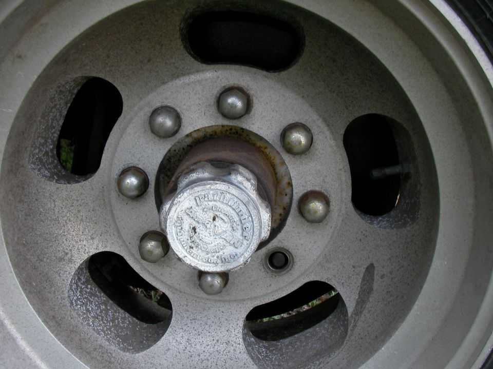 Close-up of a vehicle's wheel hubcap with visible lug nuts and some text on the cap
