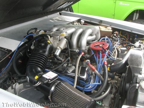 1968 Ford Mustang - Close-up of a V8 engine, with a green Ford Bronco visible behind it.
