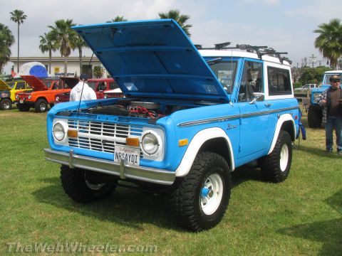 1968 Ford Mustang - A blue 1970 Ford Bronco is displayed with its hood open, alongside other vehicles at an outdoor event.
