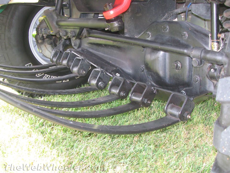 Leaf spring suspension system with multiple curved springs attached to a black axle housing