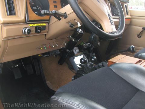 1968 Ford Mustang - The interior of a vehicle shows a tan dashboard, steering wheel, and floor shifter, with visible gauges and switches.