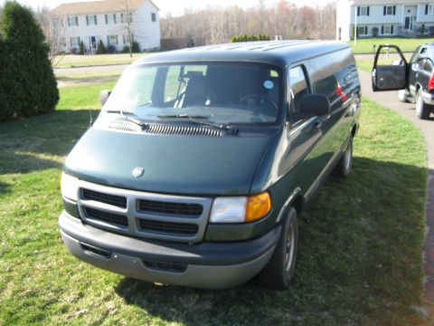 1994 Ford Bronco - A dark green van is parked on a grassy lawn in front of a residential building.
