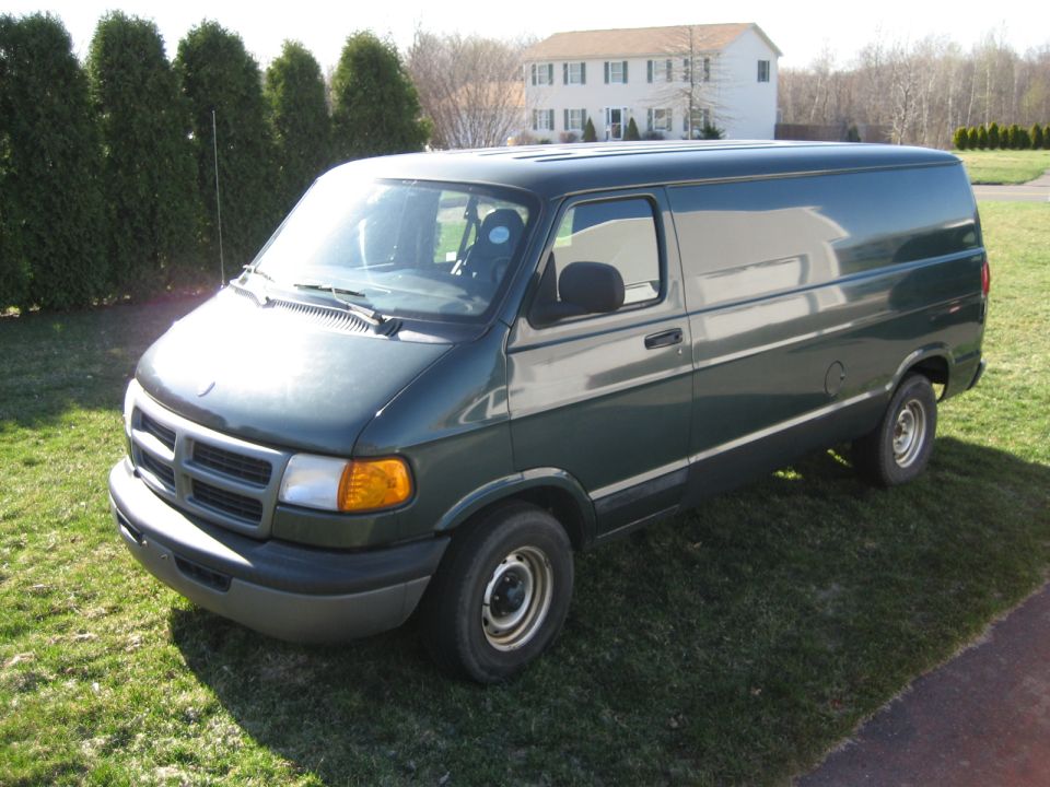 Dark green Dodge Ram cargo van parked on grass, three-quarter front view