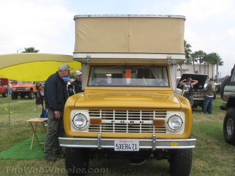 1968 Ford Mustang - A yellow Ford Bronco with a pop-up camper is parked on a grassy field with other vehicles and people around.