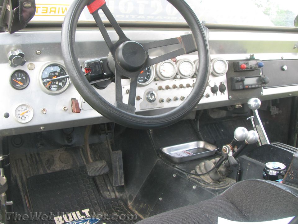 Interior view of a vehicle with a custom dashboard, aftermarket gauges, and a manual transmission