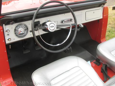 1968 Ford Mustang - The interior of a red 1968 Ford Bronco features silver seats and a classic Ford steering wheel with visible instrumentation.