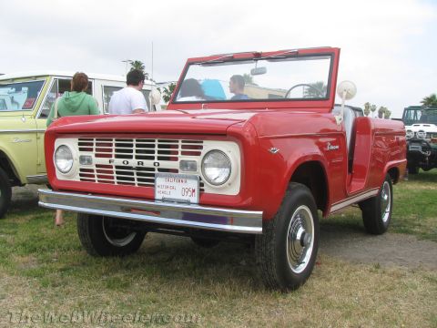 1968 Ford Mustang - A red 1968 Ford Bronco convertible is parked on grass next to another vehicle.