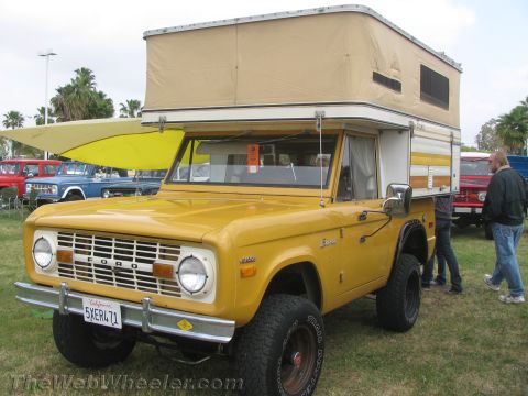 1968 Ford Mustang - This yellow 1970 Ford Bronco is equipped with a pop-up camper shell, seen at an outdoor event with other vehicles.