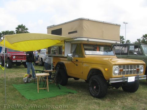 1968 Ford Mustang - A yellow Ford Bronco with a camper shell and awning is parked on grass, with other vehicles nearby.