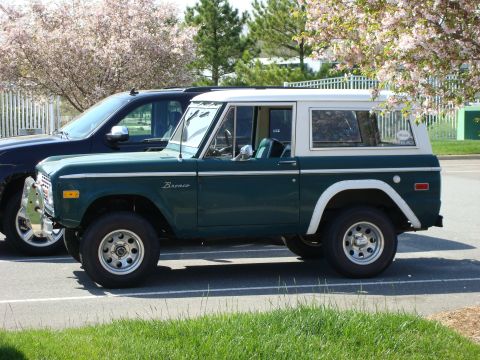 1977 Ford Bronco - A classic green 1977 Ford Bronco is parked next to a modern SUV.