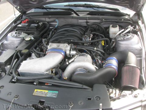 1968 Ford Mustang - The engine bay of a modern Ford Mustang features a prominent supercharger and custom air intake system.