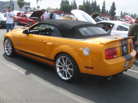 1968 Ford Mustang - A yellow convertible Mustang is parked at a car show with other vehicles visible.