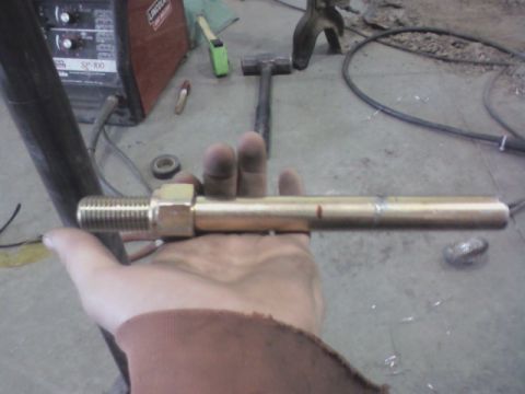 1992 Ford F-350 - A brass fitting is held in a hand with a Lincoln welder and tools in the background.