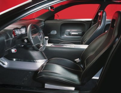 2004 Ford 427 - The interior of a black car is shown, bucket seats, a steering wheel, and dashboard details against a red background.
