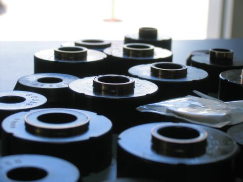 1984 Ford Bronco - Several suspension bushings are laid out on a surface, some showing part numbers.
