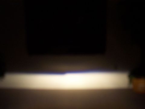 1993 Ford Probe - A bright beam from a car's headlight cuts through the darkness, casting light on a surface below.